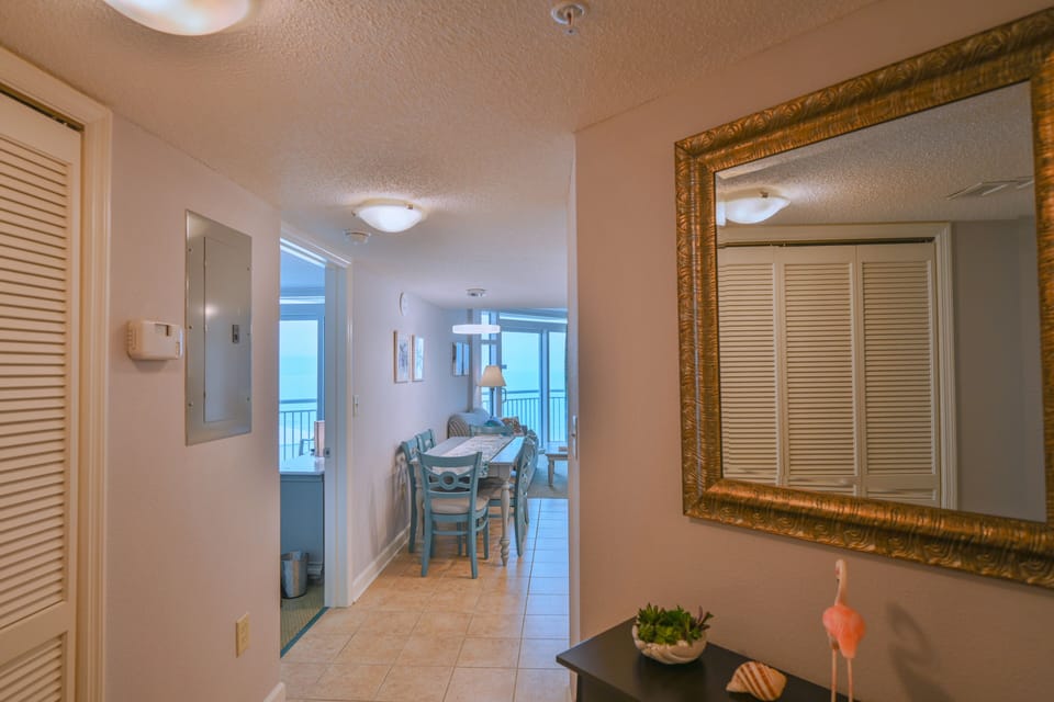 Bright entryway with mirror leads to oceanfront living room & bedroom.