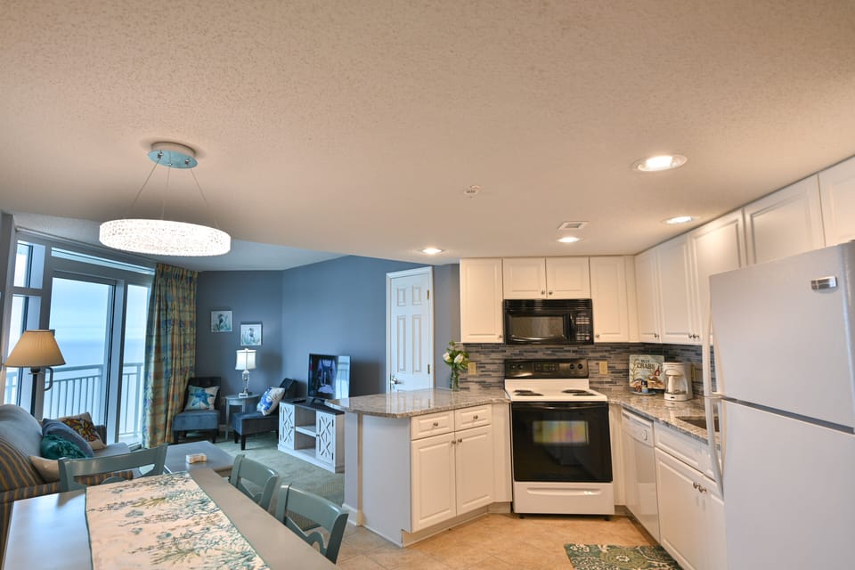 Updated kitchen with sleek white cabinetry and black appliances.