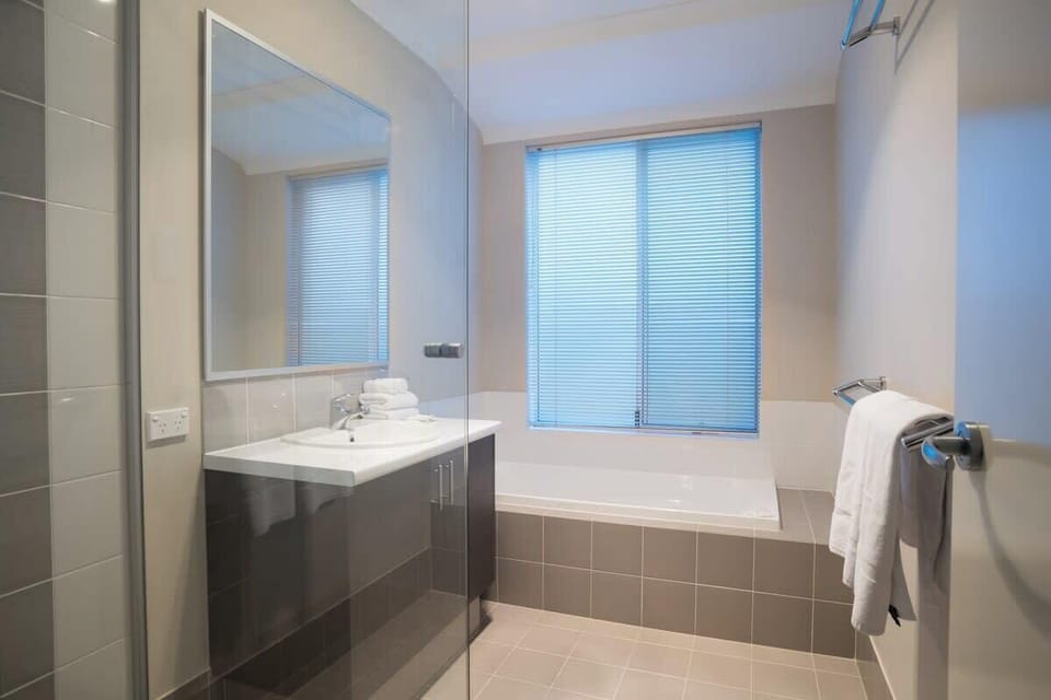 A spacious main bathroom with a glass-enclosed shower, bathtub, and fresh towels provided.