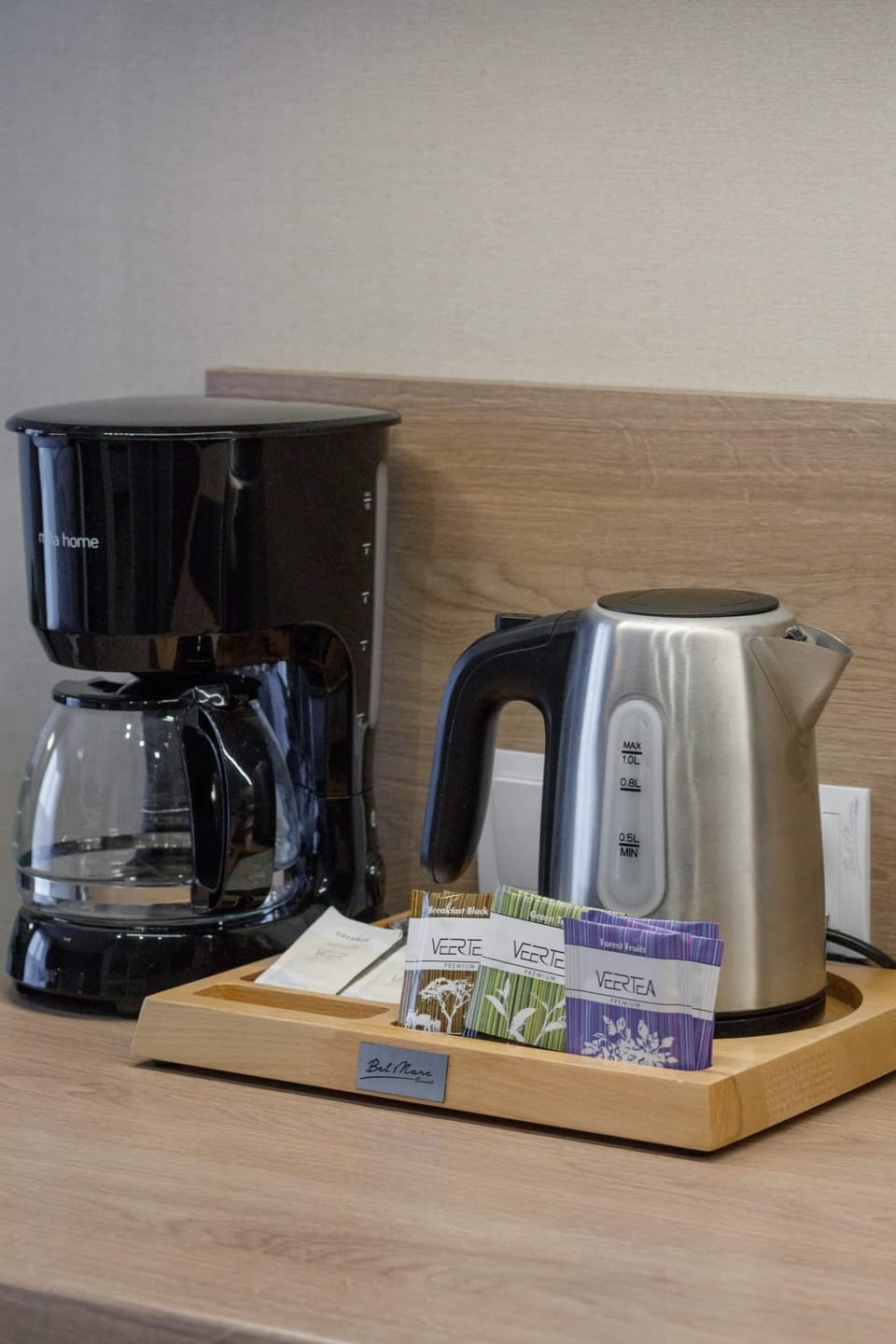 A close-up of a coffee station with a coffee machine, kettle, and mugs, highlighting guest amenities.
