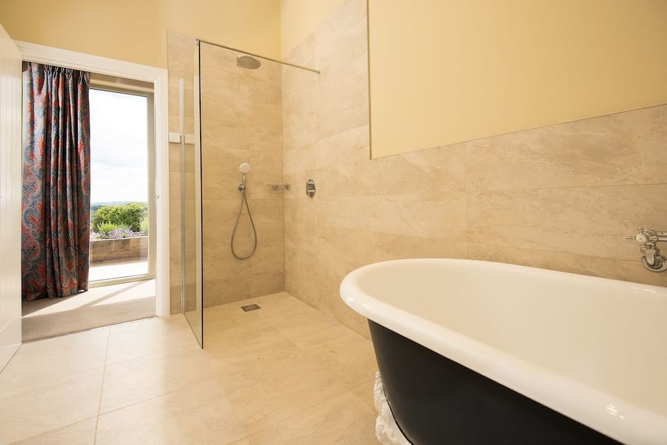Shepherd's House - bedroom one en-suite walk-in wet room shower with separate roll top bath, heated towel rail, basin and WC