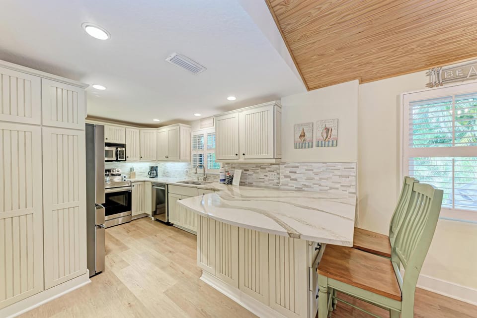 Your fully equipped kitchen awaits with marble countertops, modern appliances, and coastal charm—perfect for preparing meals together.