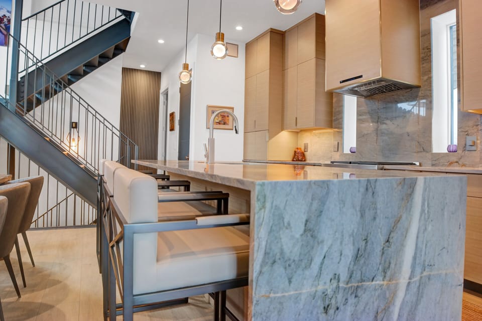 The kitchen has a grey quartz waterfall island with additional bar seating for 4, and pendant lighting above the island.
