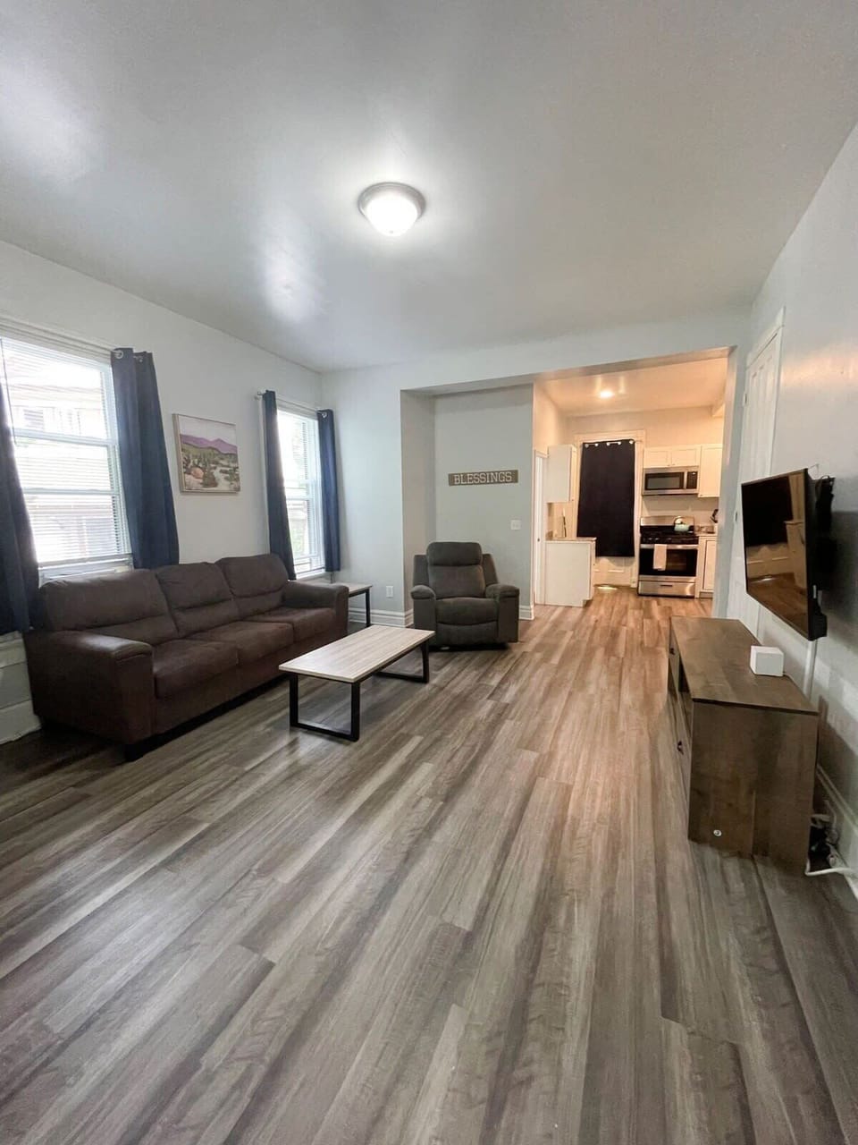 Open living and kitchen space with natural light, a comfy couch and recliner.