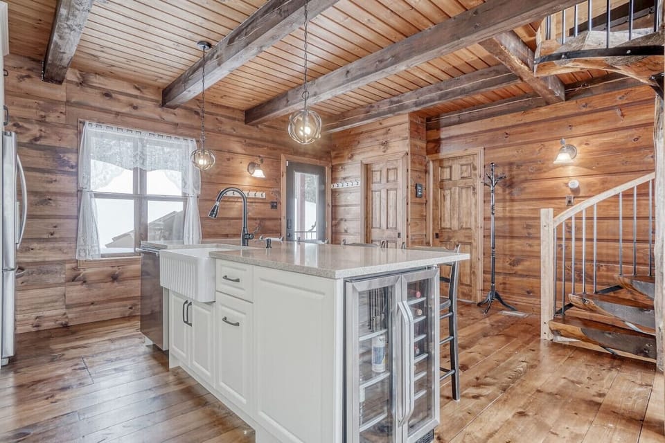 A second angle of the kitchen island and farmhouse sink, with stairs to the lower level.