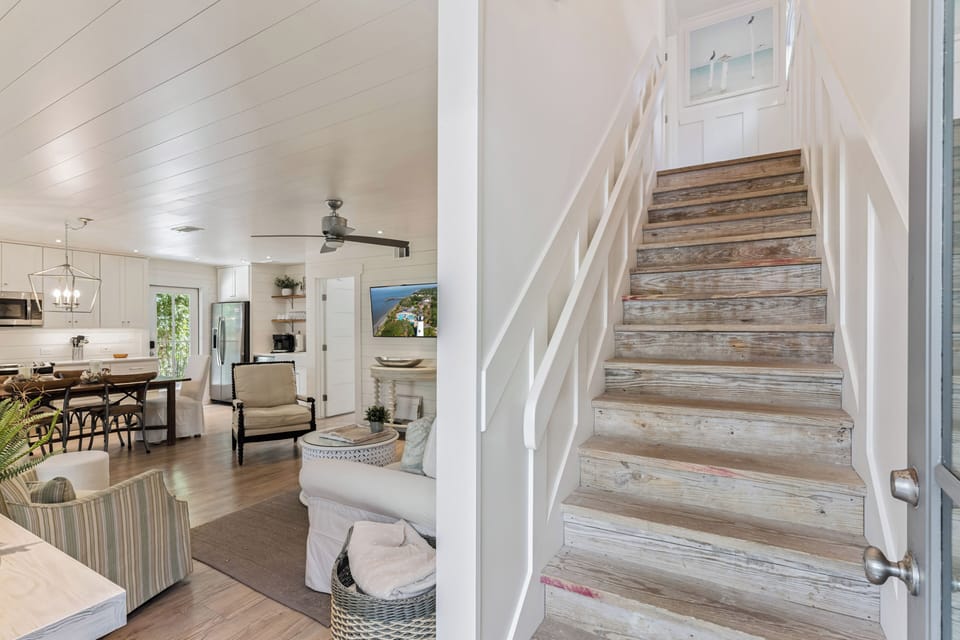 Step into your bright, open living space where rustic wood stairs meet coastal charm in this beautifully designed retreat.