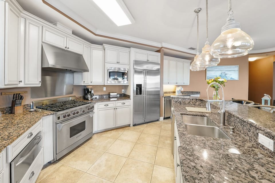 Prepare memorable meals in this chef-inspired kitchen featuring granite counters, premium appliances, and elegant pendant lighting.