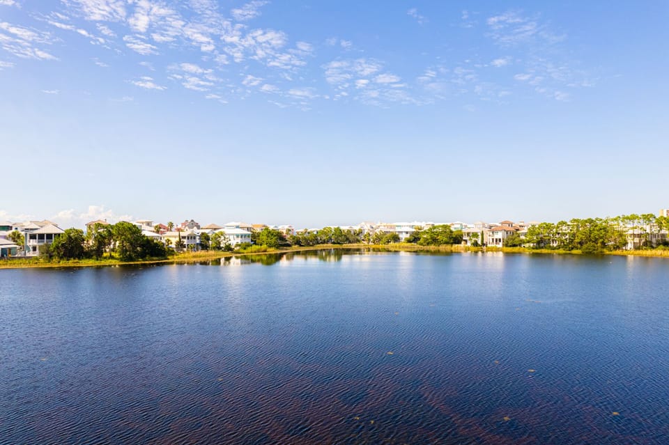 Serene lakefront community with beautiful homes nestled among lush trees under a picturesque sky.