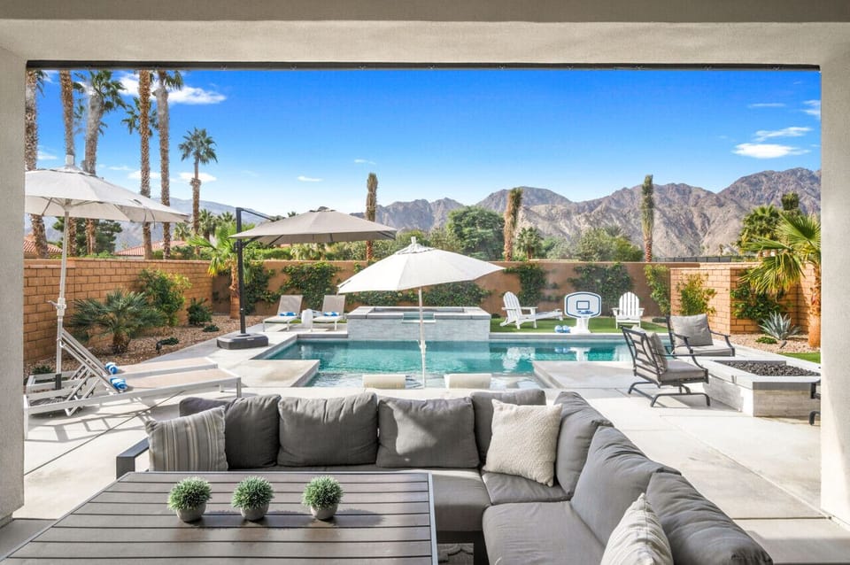 Outdoor lounge w/ plush seating, pool views & mountains in the distance