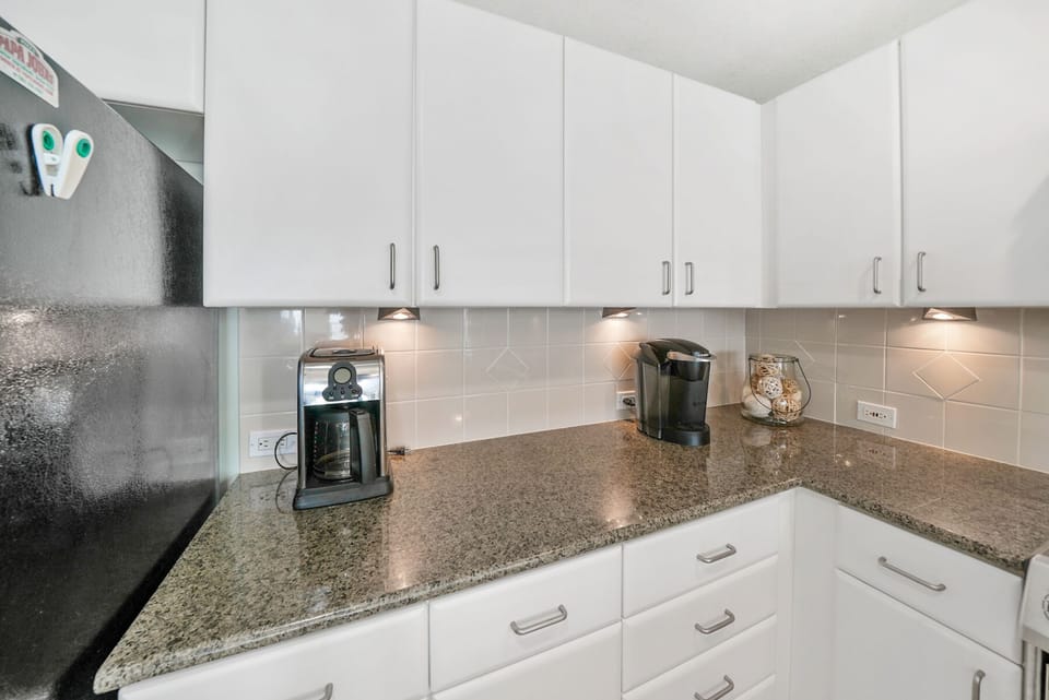 Your sleek kitchen features granite counters, modern appliances, and everything needed for morning coffee or cooking favorite meals.