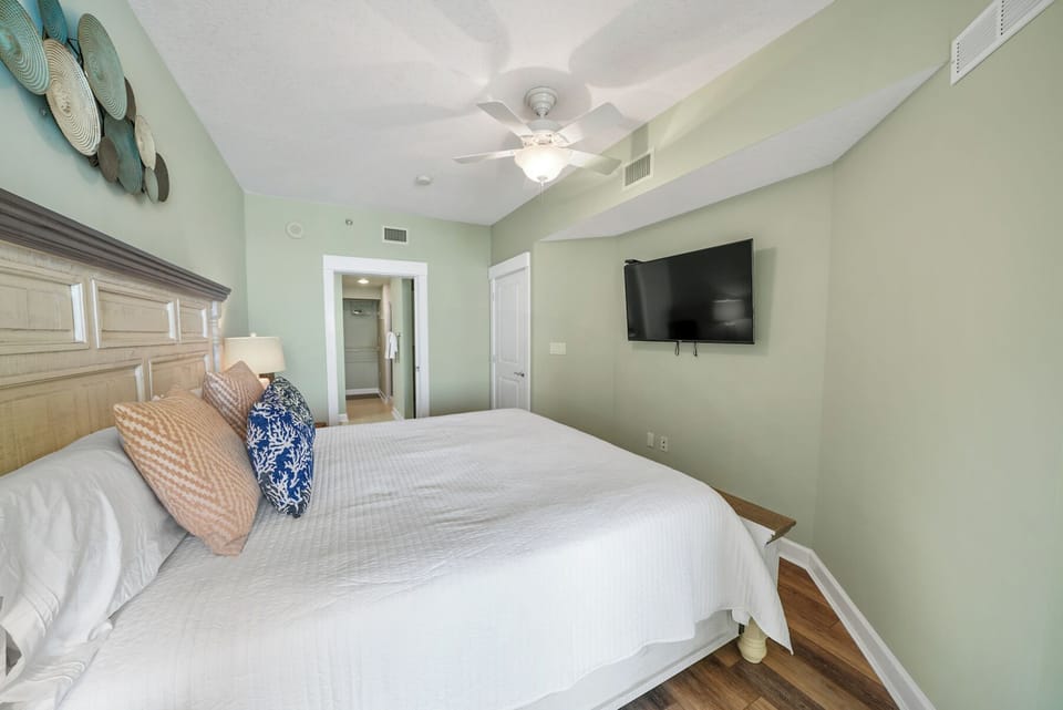 Unwind in your peaceful bedroom featuring crisp linens, coastal decor, and a flat-screen TV for your comfort.
