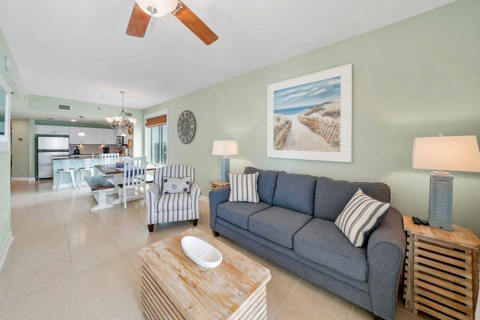 Unwind in your bright, coastal-inspired living space with comfortable seating, open kitchen, and soothing decor perfect for relaxation.