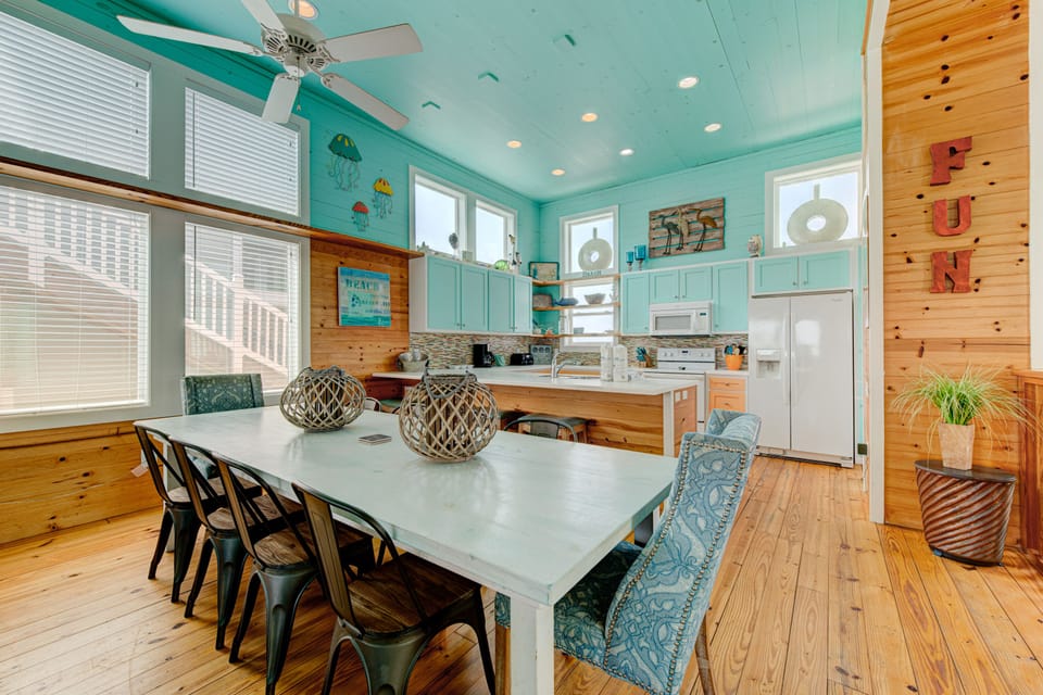 Your beach-themed kitchen invites family gatherings with coastal charm, turquoise cabinets, and spacious dining for memorable meals together.