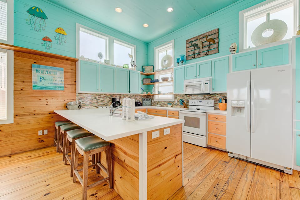 Your bright coastal kitchen invites family cooking with spacious island seating and cheerful turquoise cabinets.