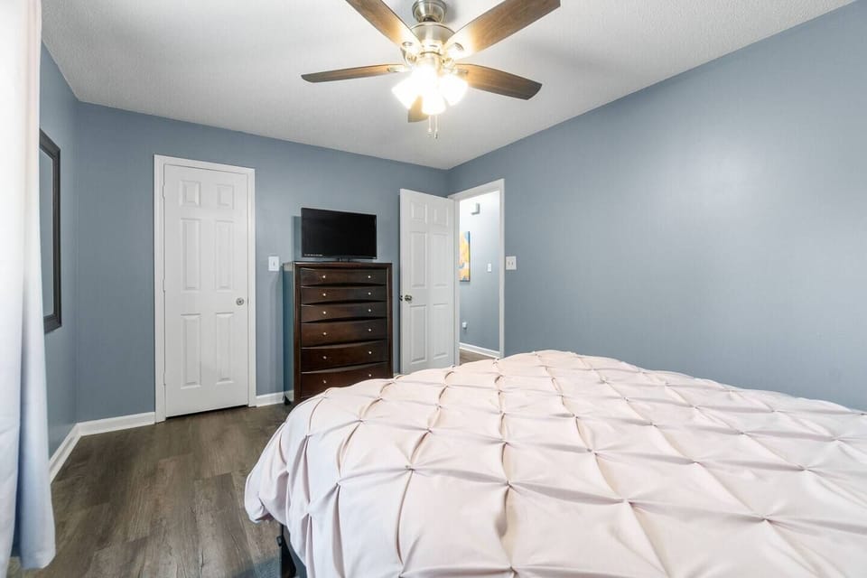 Enormous primary bedroom with walk-in closet offers plenty of storage, TV, high speed internet, alarm clock, nightstand, natural light, blinds and curtains, ceiling fan, queen sized bed with extra bedding central heating and air conditioning and more. 
