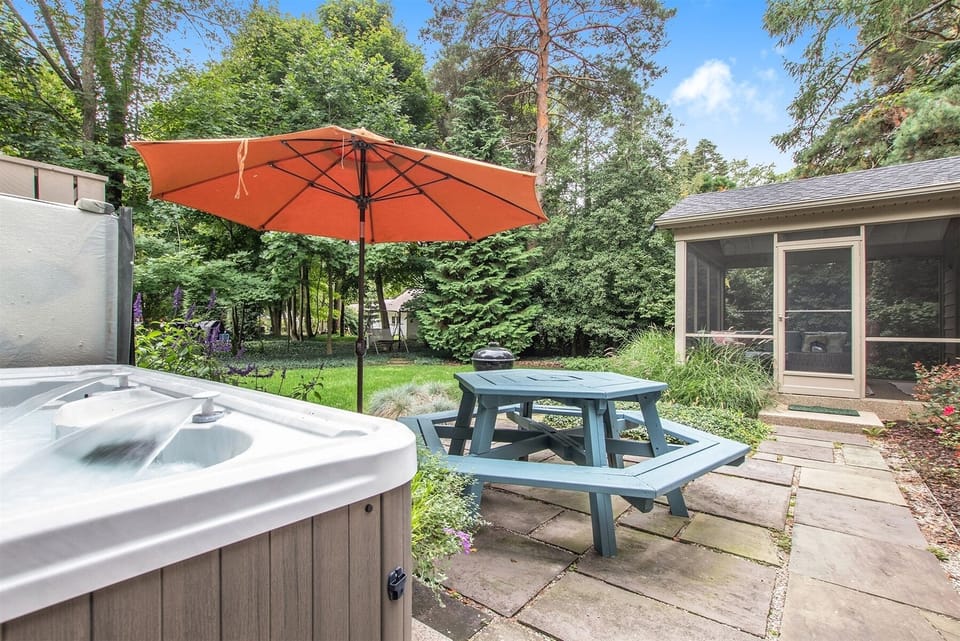 Daisy Cottage has a beautiful backyard setting with a picnic table on the patio and the relaxing hot tub