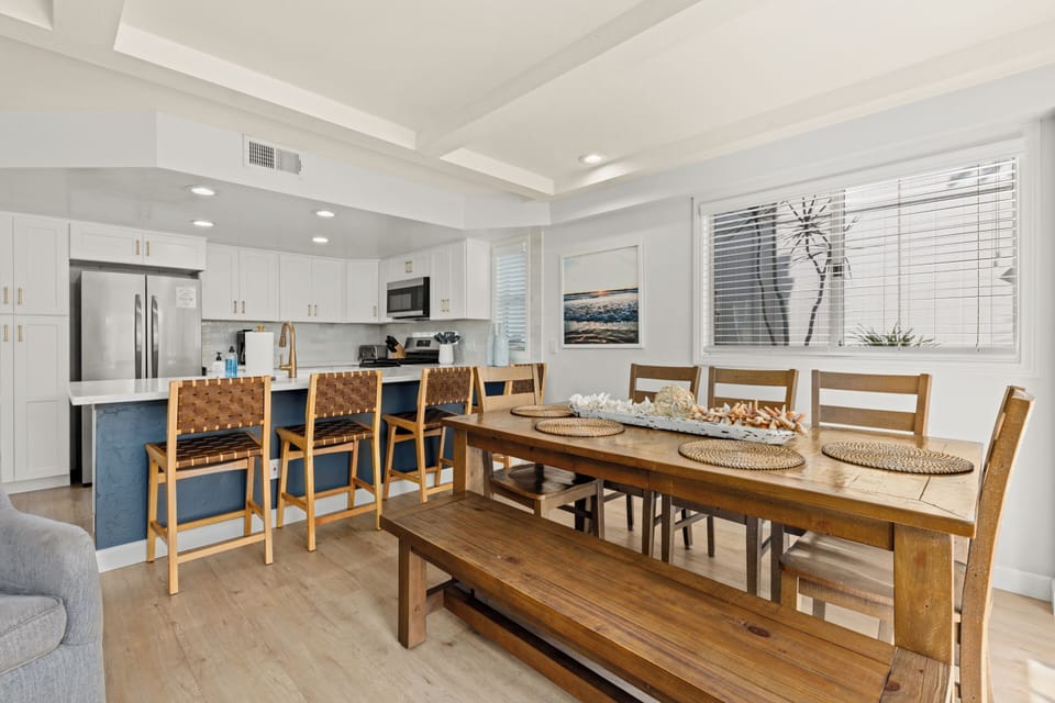 This spacious rustic-modern wooden table, complete with chairs and a bench, provides a larger, more formal dining area for an elevated culinary experience.