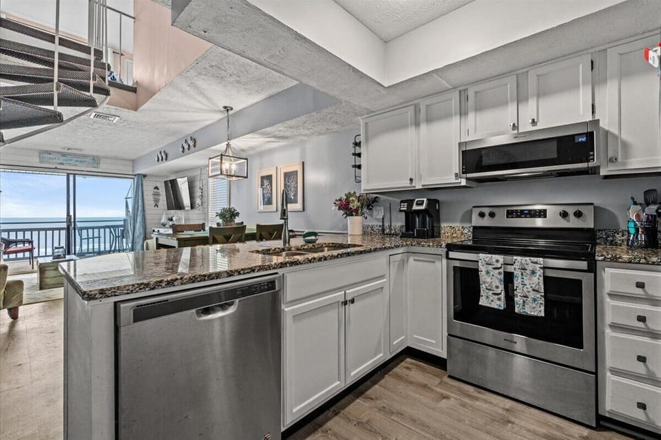 Cook your favorite meals in this fully equipped kitchen with stainless appliances, and stunning ocean views through floor-to-ceiling windows.