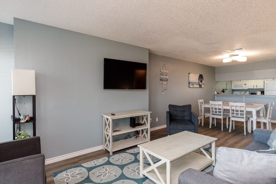 Unwind in your spacious living room featuring a large smart TV, cozy seating, and open-concept design flowing to the dining area.
