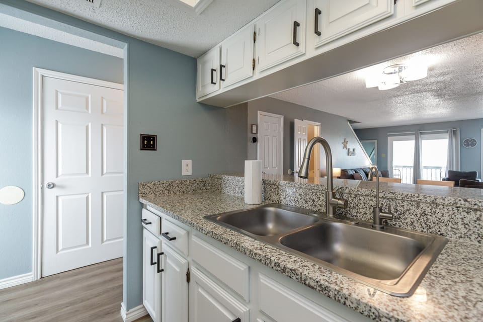 Cook your favorite meals in this bright kitchen featuring granite countertops, stainless steel sink, and modern white cabinets.