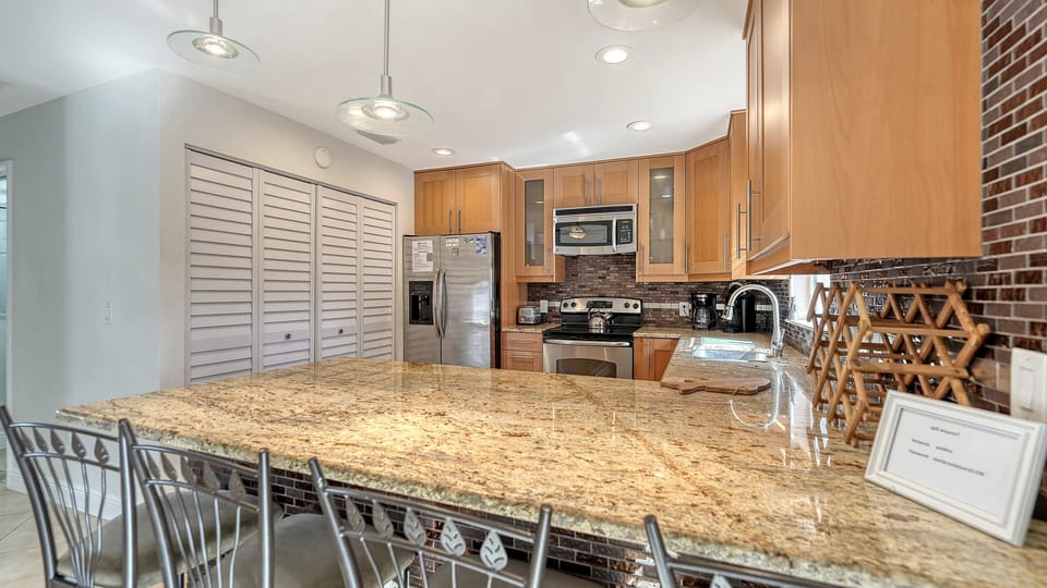Kitchen with granite countertops, full-size stainless steel refrigerator, and ample cabinet storage