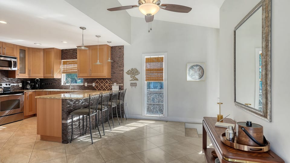 Kitchen with warm wooden cabinetry, brick-style backsplash, and bar counter with stool seating