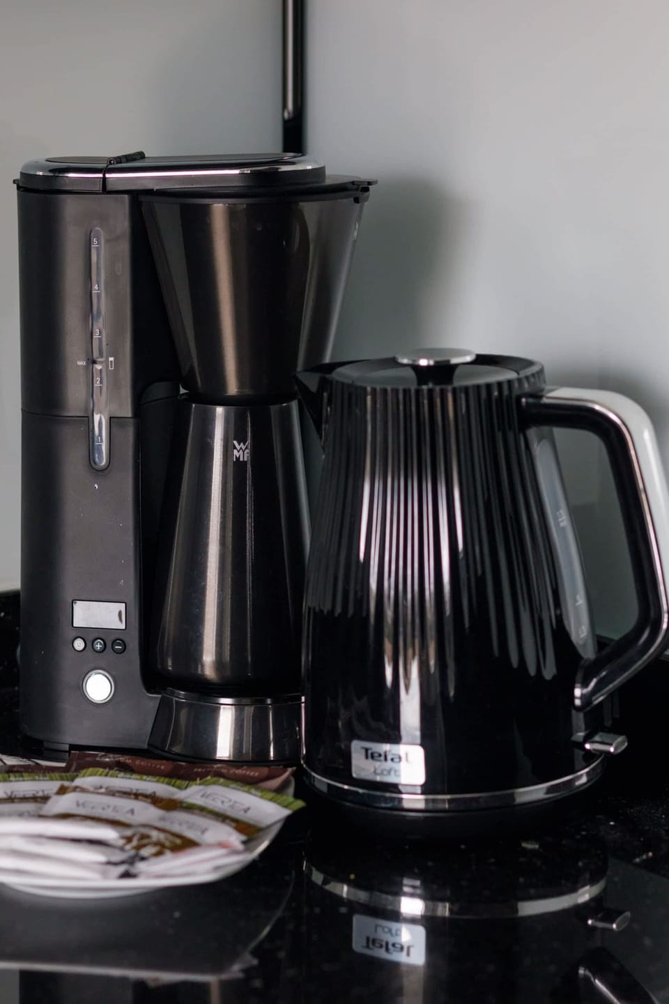 A close-up of a coffee station featuring a kettle and other accessories for guests.
