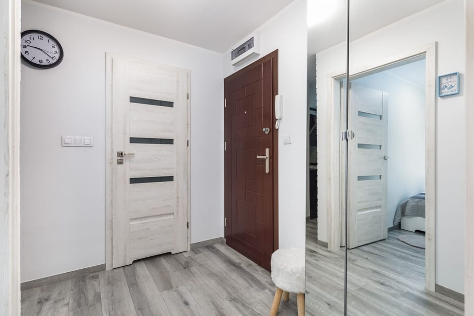 Bright hall with a mirror, doors and minimalist decor.
