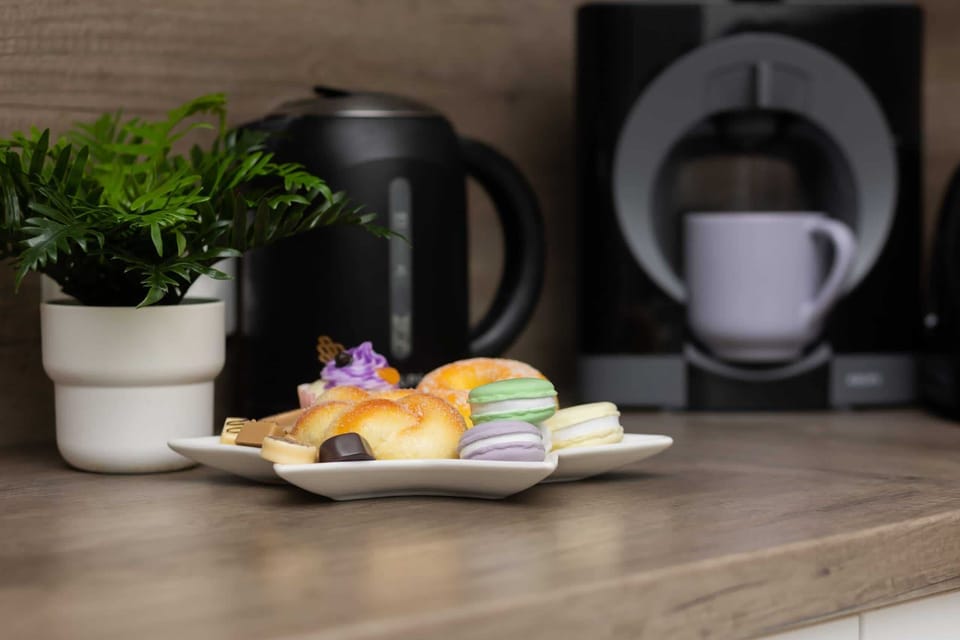 A close-up of a coffee station with a modern kettle, coffee maker, and greenery.
