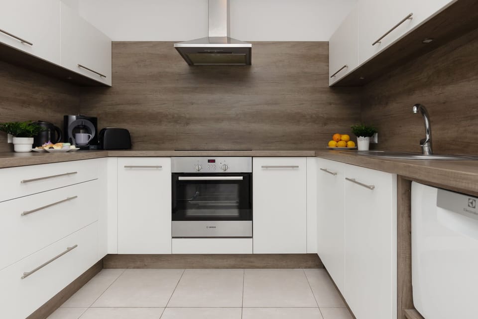 A fully equipped kitchen with sleek white cabinets and stainless steel appliances.
