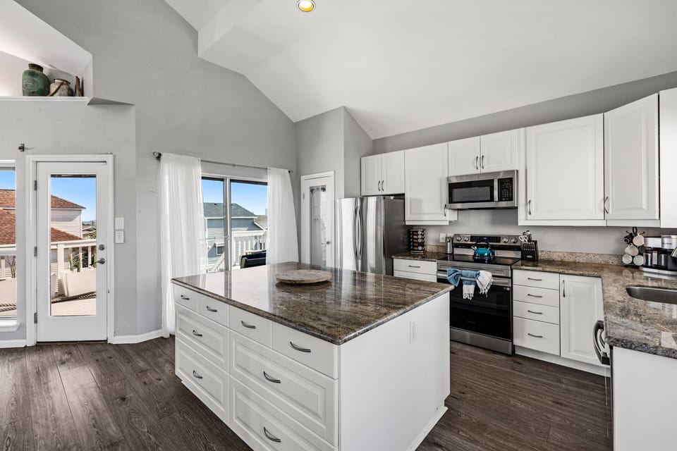 Spacious fully equipped kitchen with stainless steel appliances, granite countertops, custom cabinetry, and open floor plan for family meals.