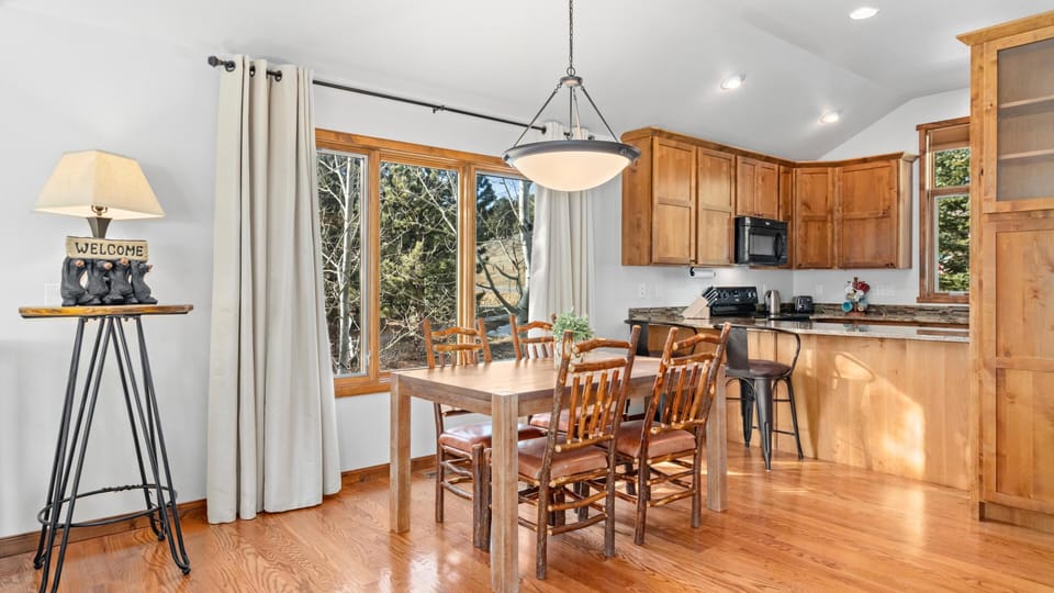 Sunlit dining area with forest views and cozy kitchen access