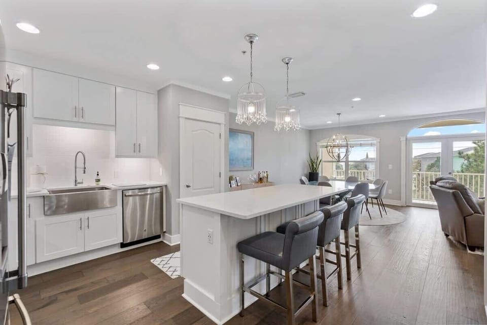 - Spacious open concept kitchen flows into the dining area with natural light & easy outdoor access - Large island seats four with plush stools, ideal for meals or socializing - White cabinetry & stainless steel appliances add a sleek, polished look