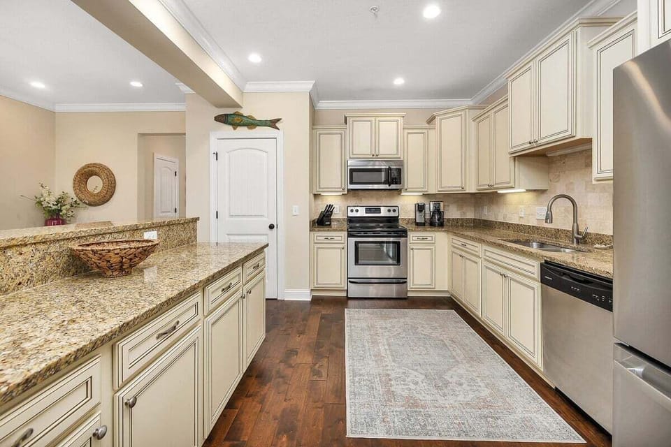 Kitchen with cream cabinets, granite island, and stainless appliances