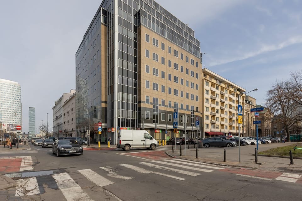 An external view of a city street with a prominent yellow building on the corner.
