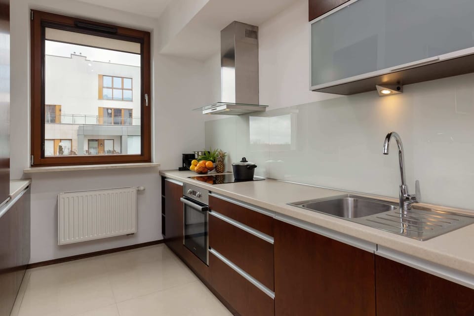 A modern kitchen with sleek white and wooden cabinets and ample natural light.
