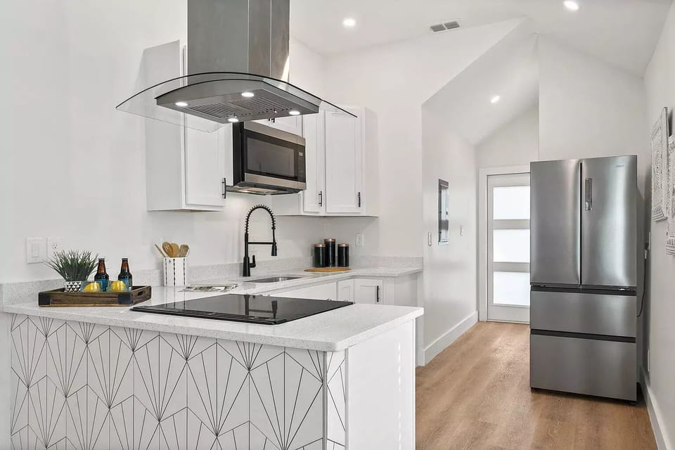 Kitchen with pots, pans, utensils, plates/bowls, and wine and drinking glasses.