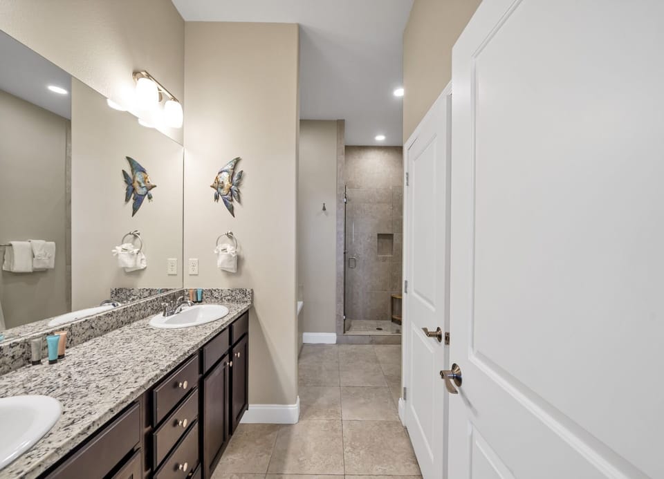 Dual granite vanities and ample counter space in this sleek, well-lit master bathroom.