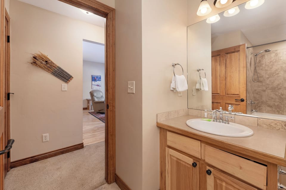 Your elegant bathroom features warm wood accents and modern lighting, creating a welcoming space to refresh after your mountain adventures.