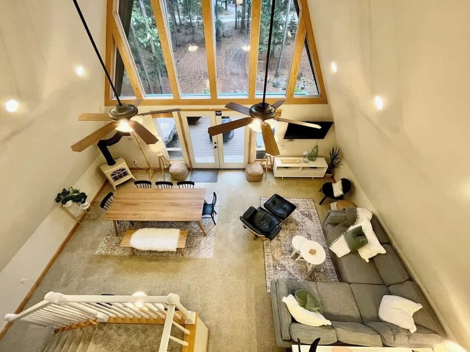 The top story has a loft that overlooks the open concept of the living room, dining area, and the beautiful views of the forest right outside the large windows
