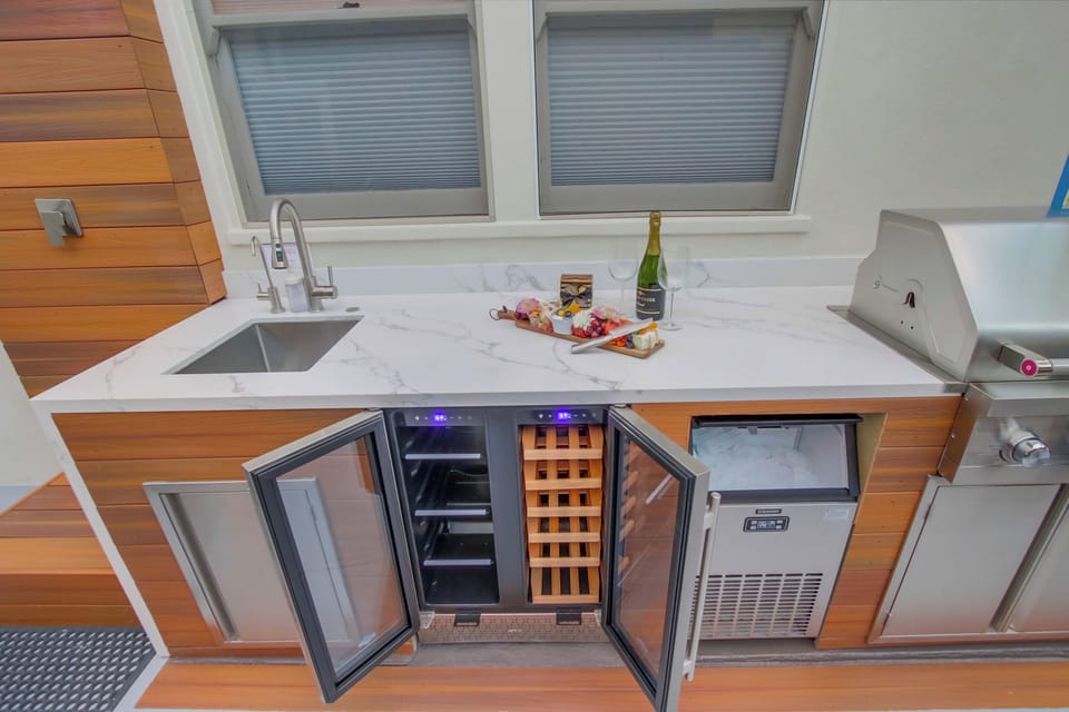 Fully equipped outdoor kitchen with grill, wine fridge, and ice machine.