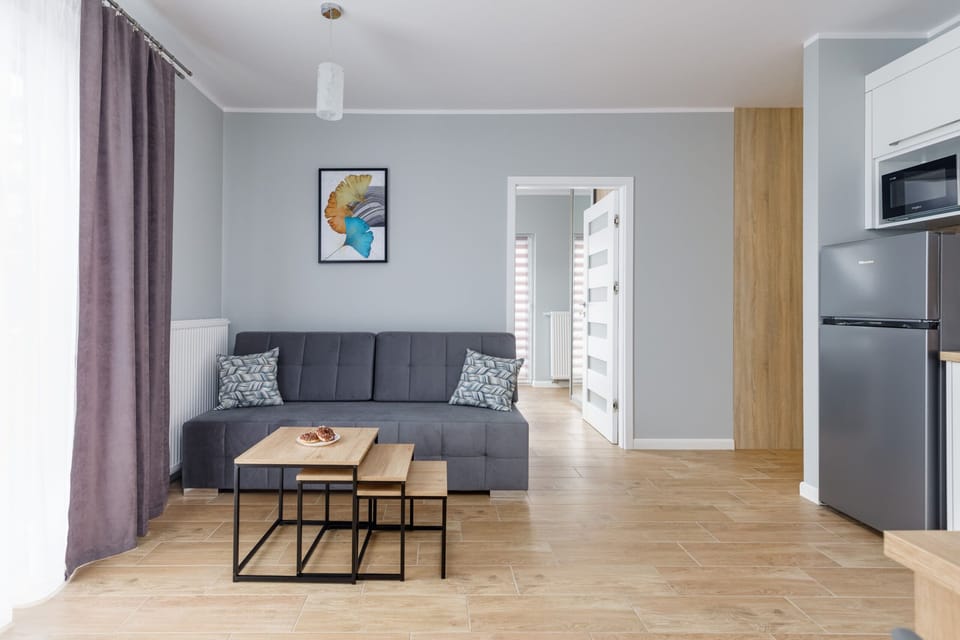 A living room with a sofa and TV, decorated in bright tones with a stylish painting.

