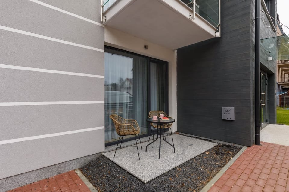 An exterior view of the apartment’s private patio area, featuring a small round table, chairs, and gravel accents.
