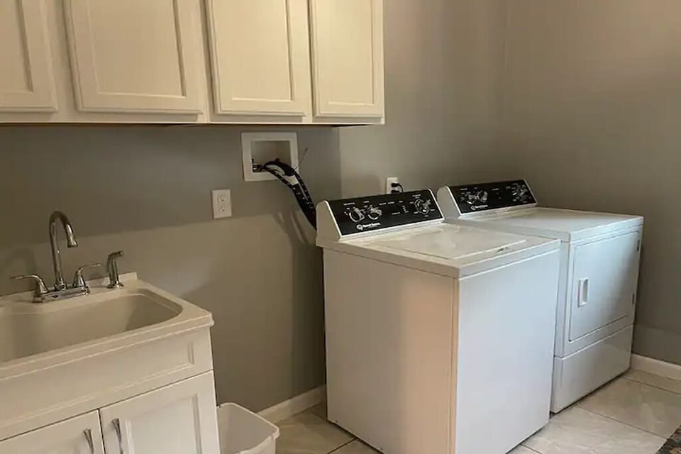 Dedicated laundry room with washer, dryer, utility sink, and storage.