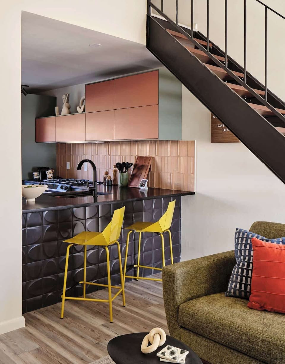 Imagine yourself enjoying your morning coffee on the vibrant yellow bar stools against the stylish black accent tiles.