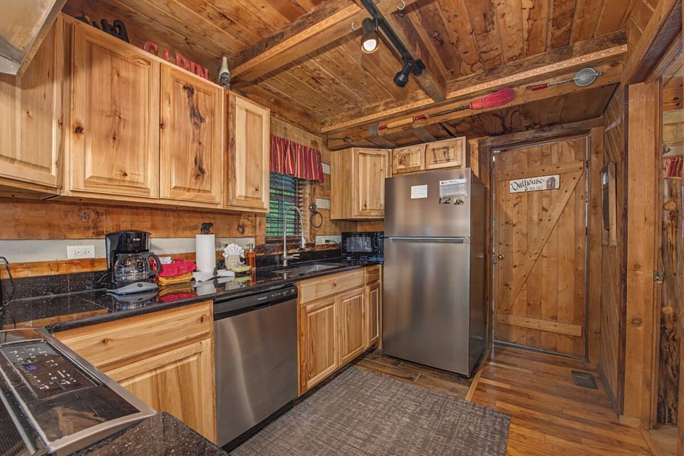 Your fully equipped kitchen offers rustic charm with modern conveniences, featuring stainless steel appliances, granite counters, and warm knotty pine cabinetry perfect for preparing your favorite meals.