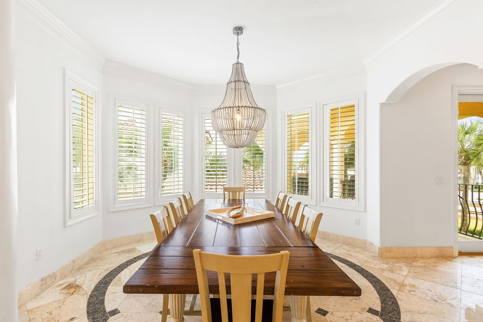 Gather around this elegant dining table for memorable meals with stunning natural light streaming through plantation shutters.