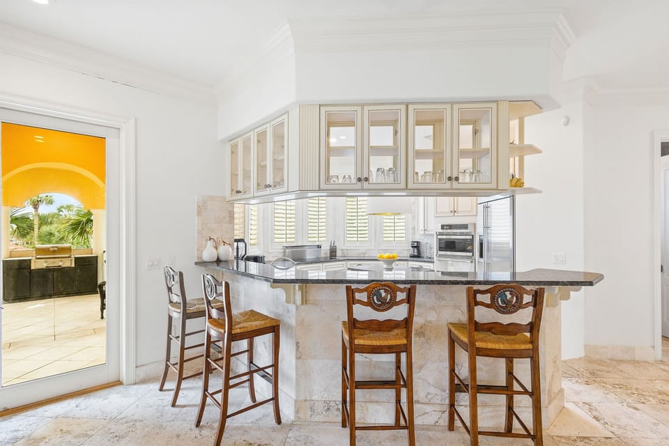 Your spacious kitchen features granite countertops and elegant bar seating where you'll enjoy morning coffee with tropical garden views.