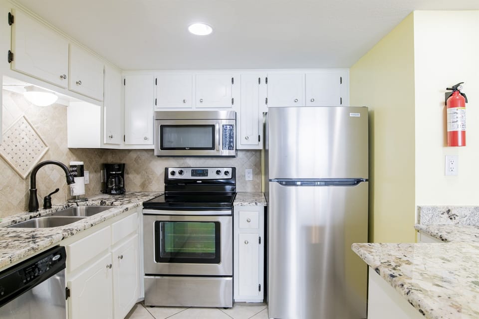 Kitchen With Stainless Steel Appliances, Coffee Maker, Blender, Mixer, Toaster And Plenty Of Pots, Pans And Dishes And Tiled Backsplash