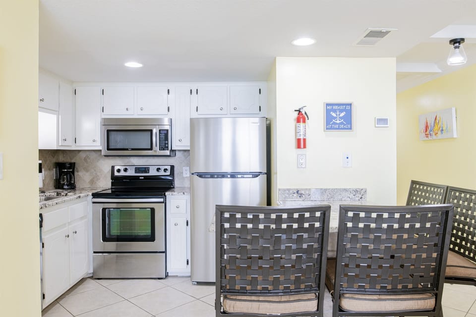 Kitchen With Stainless Steel Appliances, Coffee Maker, Blender, Mixer, Toaster And Plenty Of Pots, Pans And Dishes And Tiled Backsplash